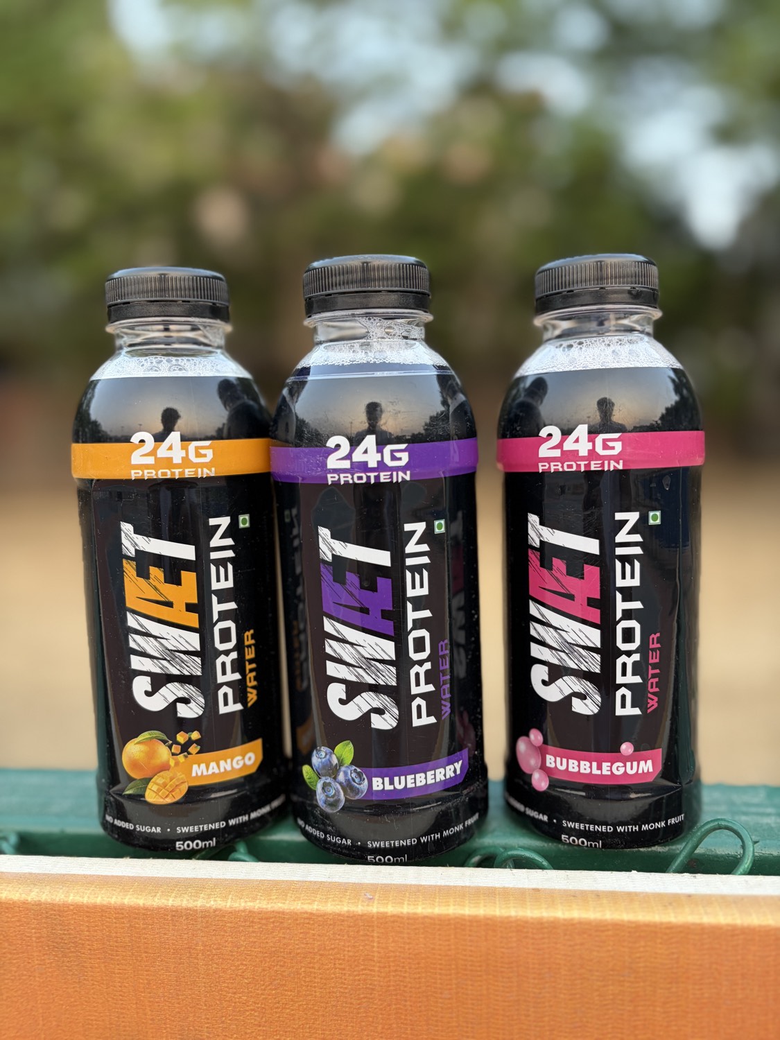 SWÆT Mango, Blueberry and Bubblegum bottles on a courtside bench