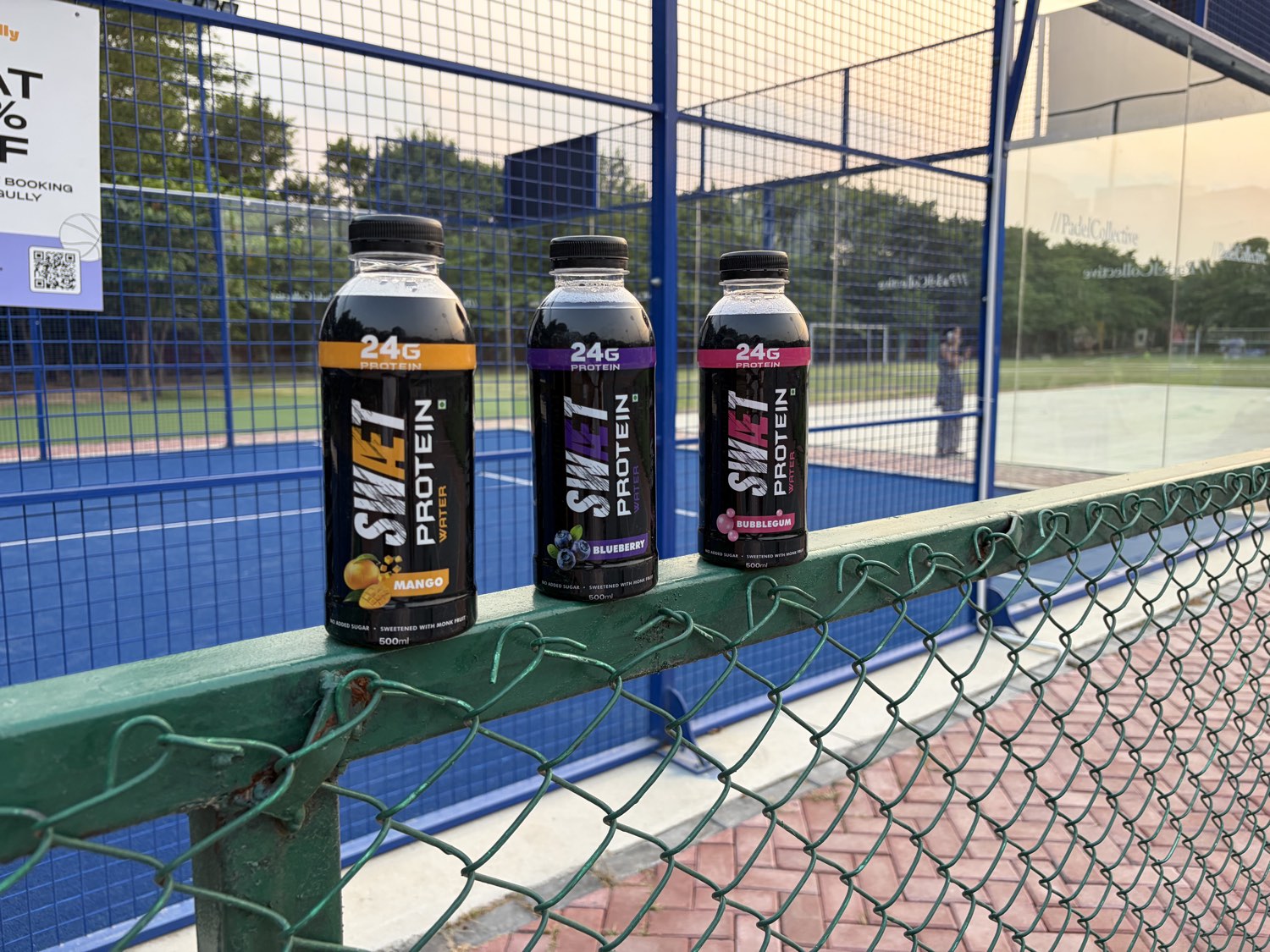 Three SWÆT flavors on a padel court fence rail